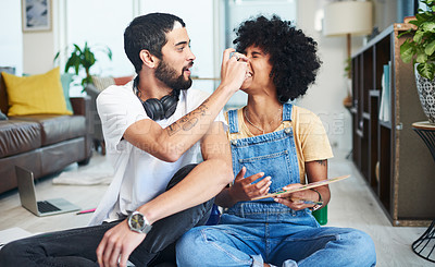 Buy stock photo Shot of a young couple enjoying themselves while painting at home