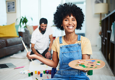 Buy stock photo Shot of a young woman holding a paint palette while her boyfriend sits in the background