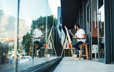 Buy stock photo Shot of a man doing a painting while sitting on the balcony at home