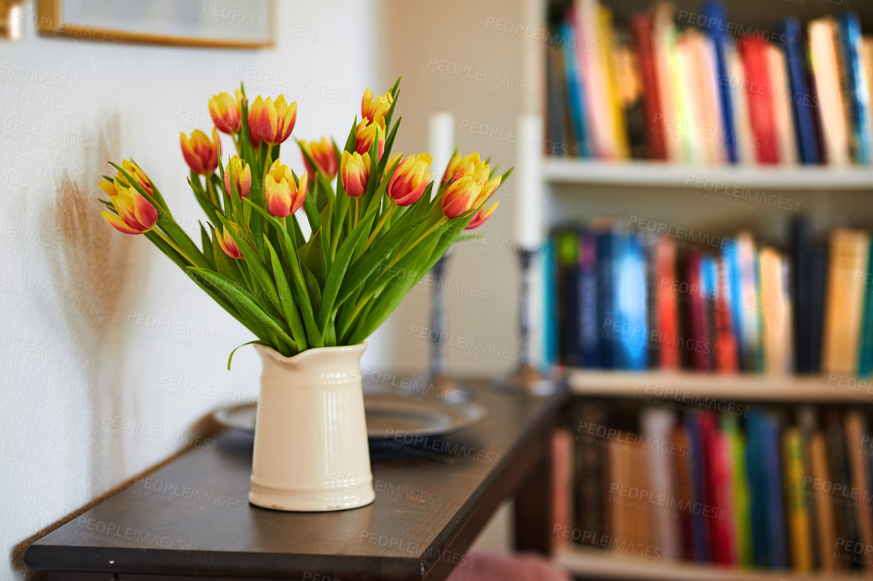 Buy stock photo Beautiful bouquet of tulips on a living room table. Pretty flowers in a vase for house decoration. Red and yellow tulip flowering plants with green stem used as home ornaments to brighten up a room