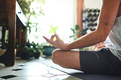 Buy stock photo Shot of an unrecognisable man meditating in the lotus position at home