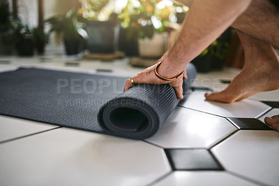Buy stock photo Cropped shot of an unrecognisable man rolling up his yoga mat at home