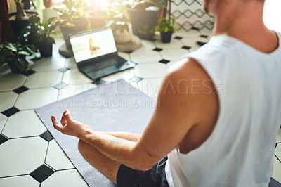 Buy stock photo Shot of an unrecognisable man using a laptop while meditating in the lotus position at home