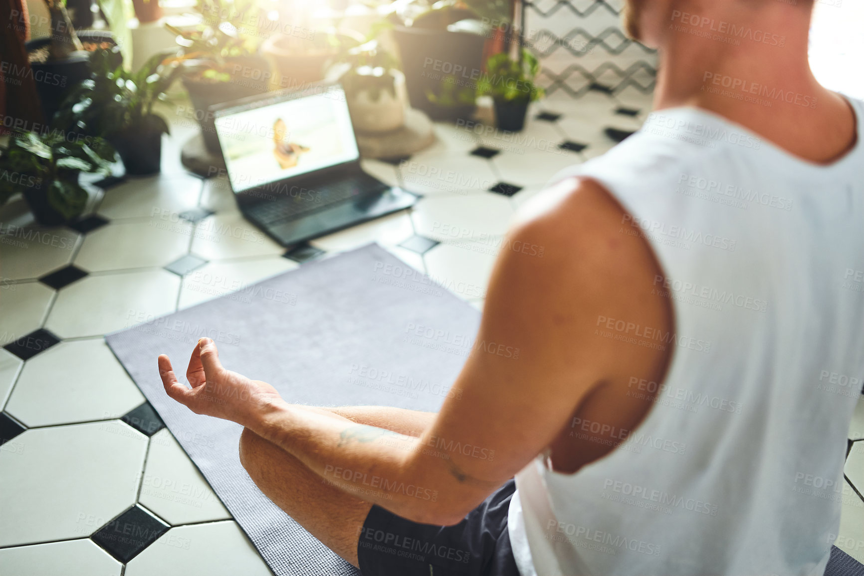 Buy stock photo Shot of an unrecognisable man using a laptop while meditating in the lotus position at home