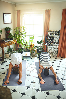 Buy stock photo Shot of two men using a laptop while going through a yoga routine at home