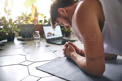 Buy stock photo Shot of a young man using a laptop while going through a yoga routine at home