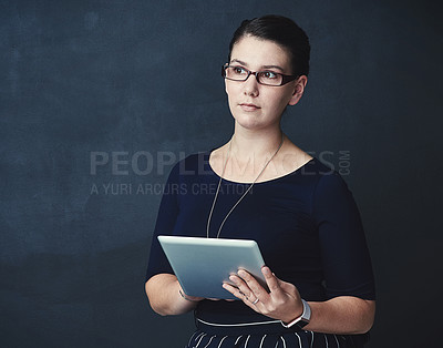 Buy stock photo Studio shot of a corporate businesswoman using a digital tablet against a dark background