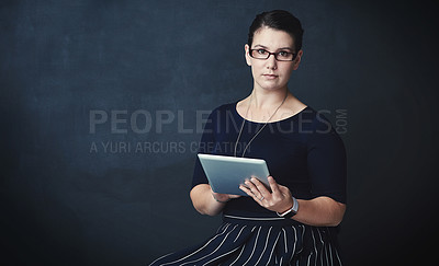 Buy stock photo Studio portrait of a corporate businesswoman using a digital tablet against a dark background