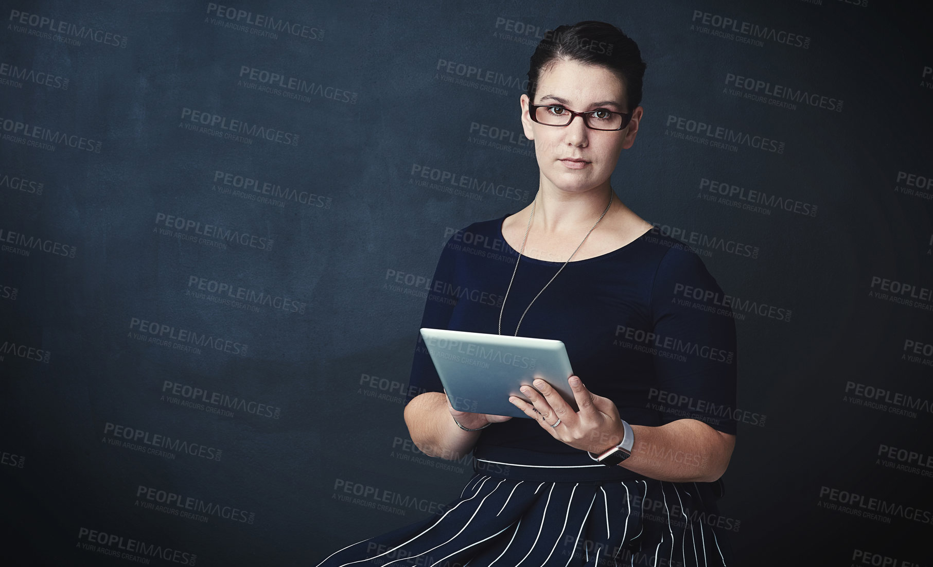 Buy stock photo Studio portrait of a corporate businesswoman using a digital tablet against a dark background