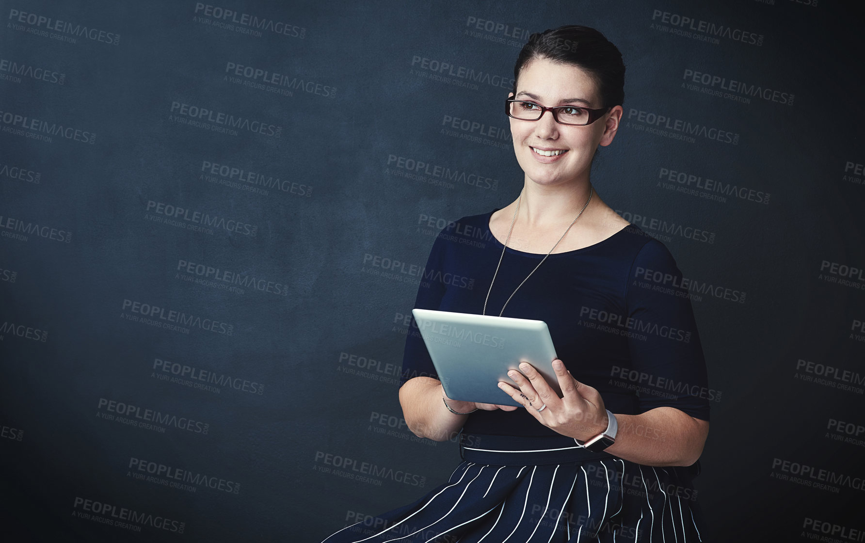 Buy stock photo Studio portrait of a corporate businesswoman using a digital tablet against a dark background