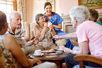 Buy stock photo Shot of a group of happy seniors playing a card game in their retirement home while a nurse watches
