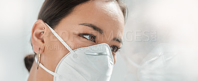 Buy stock photo Shot of a masked young businesswoman looking thoughtfully out of a window in a modern office