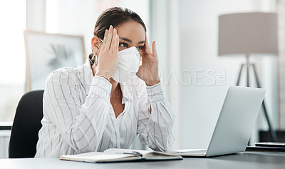 Buy stock photo Shot of a masked young businesswoman looking stressed while working at her desk in a modern office