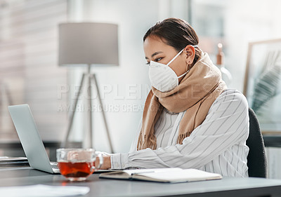 Buy stock photo Shot of a masked young businesswoman using a laptop at her desk in a modern office