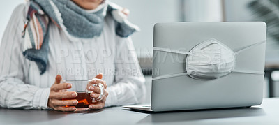 Buy stock photo Shot of a businesswoman having a glass of herbal tea while using a laptop with a mask wrapped around it