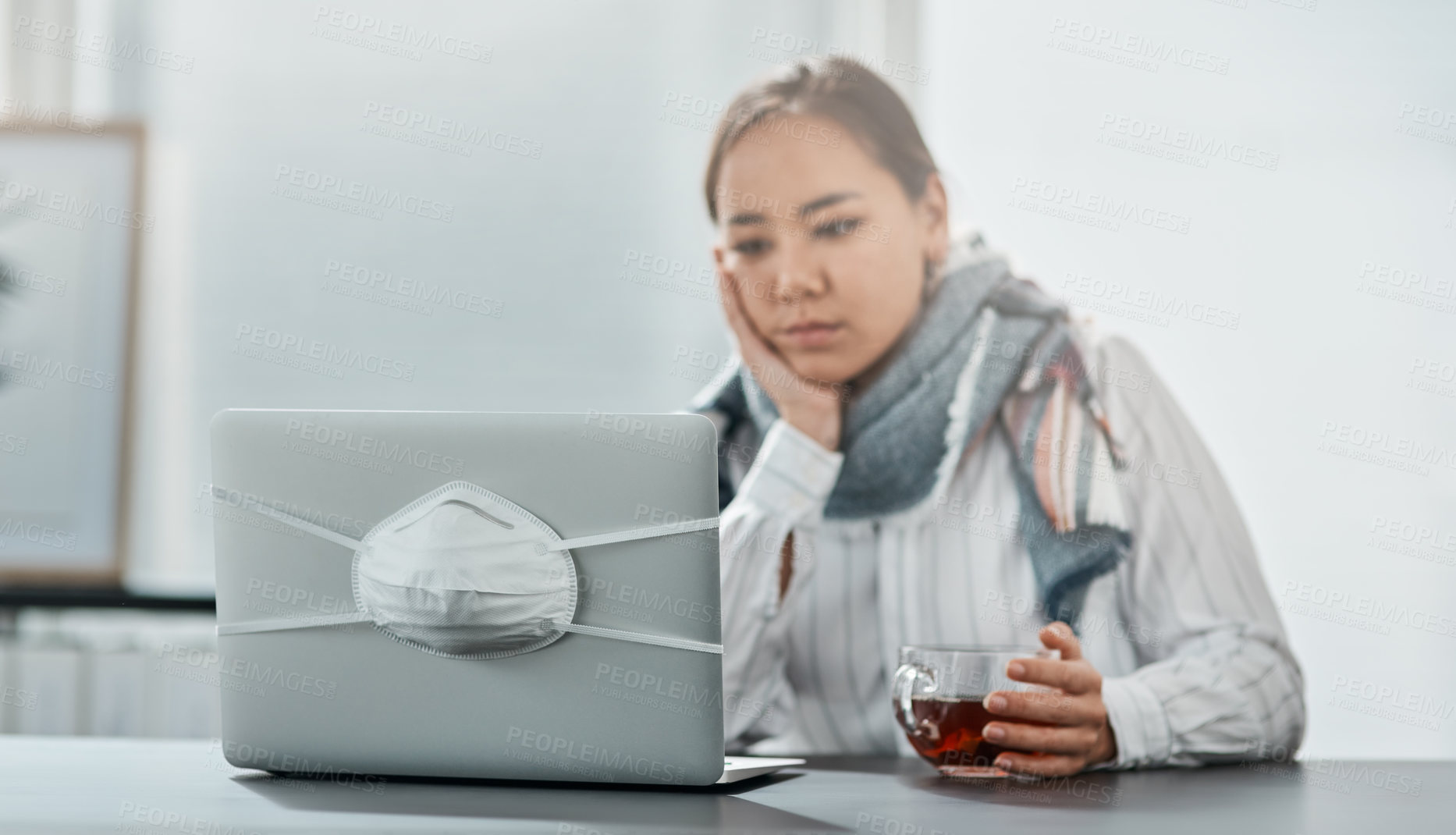 Buy stock photo Shot of an unhappy young businesswoman having a glass of herbal tea while using a laptop in a modern office