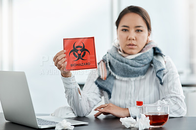 Buy stock photo Shot of a young businesswoman holding a biohazard sign at her desk in a modern office