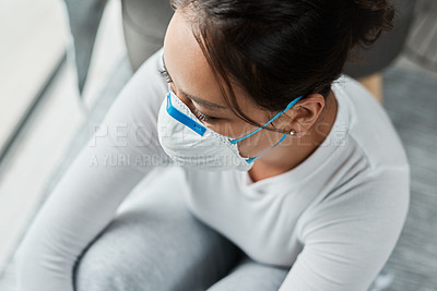 Buy stock photo Shot of a woman wearing a mask while sitting at home