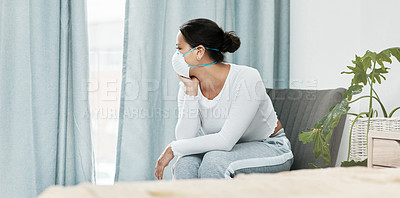 Buy stock photo Shot of a young woman wearing a mask while looking out a window at home