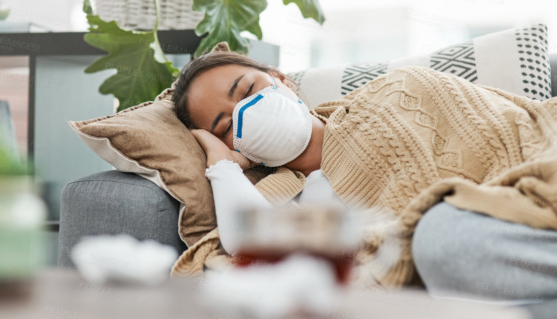 Buy stock photo Shot of a woman wearing a mask while lying sick at home