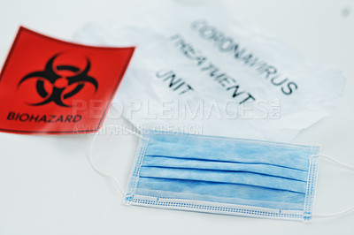 Buy stock photo Shot of a biohazard sign and a face mask against a white background