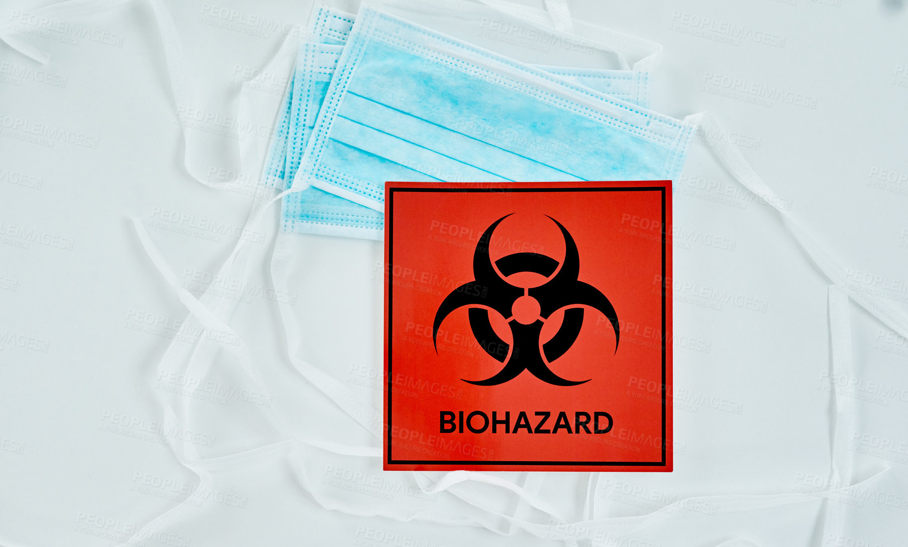 Buy stock photo Shot of a biohazard sign and a face mask against a white background