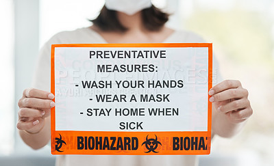 Buy stock photo Shot of a woman holding up a sign with a list of COVID-19 prevention measures