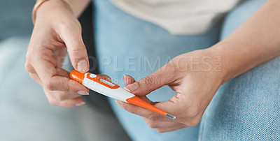 Buy stock photo Cropped shot of a woman checking her temperature on a digital thermometer