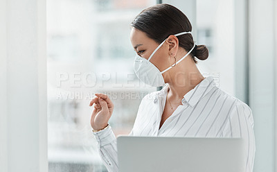 Buy stock photo Shot of a masked young businesswoman holding a laptop and waving out of a window in a modern office