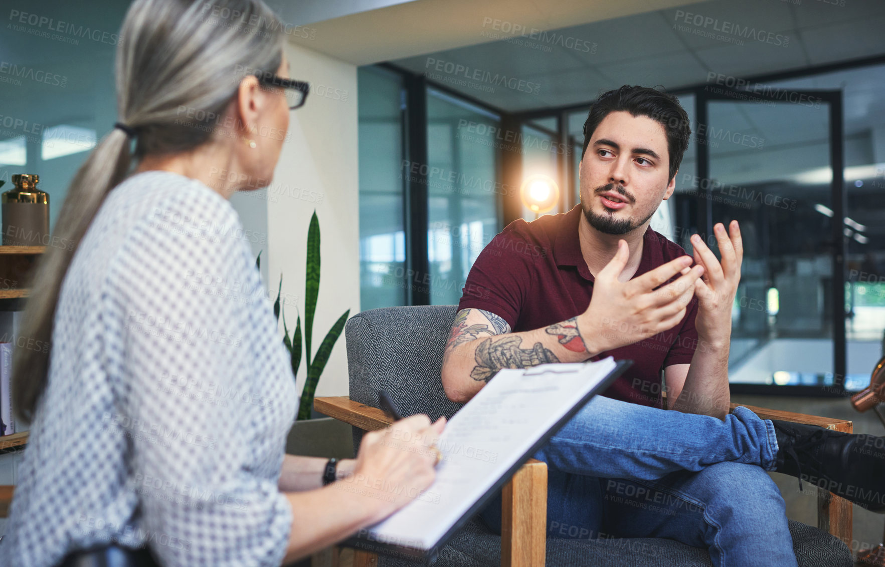 Buy stock photo Shot of a young man having a therapeutic session with a psychologist