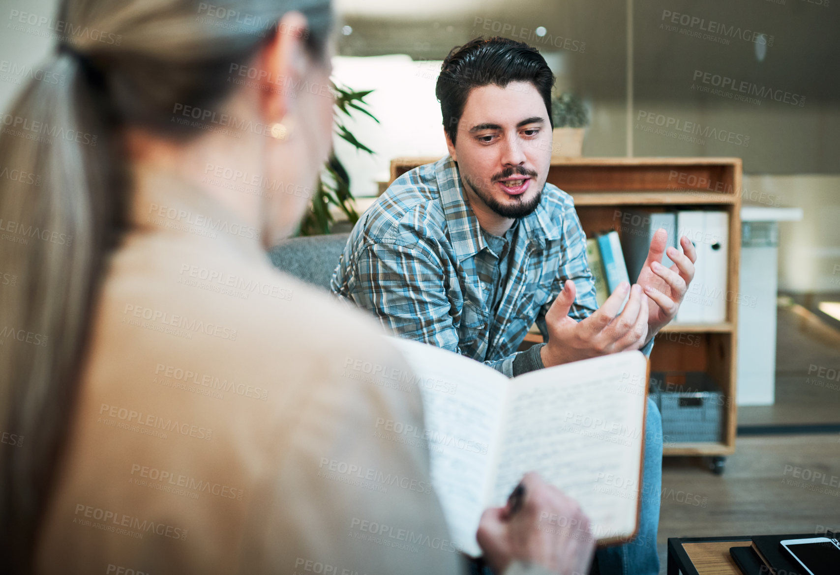 Buy stock photo Shot of a young man having a therapeutic session with a psychologist and looking upset