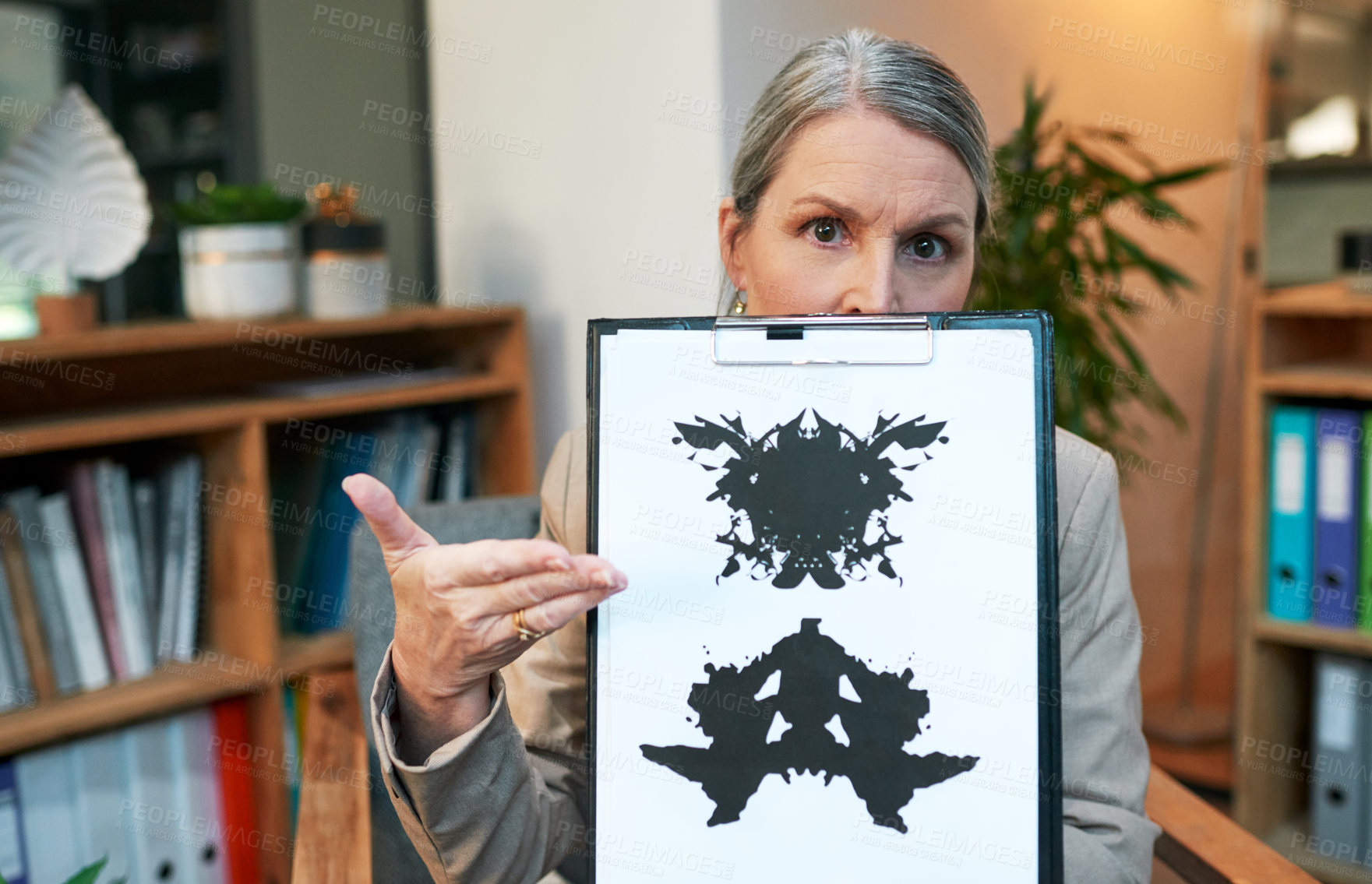 Buy stock photo Portrait of a mature psychologist holding up an inkblot test during a therapeutic session