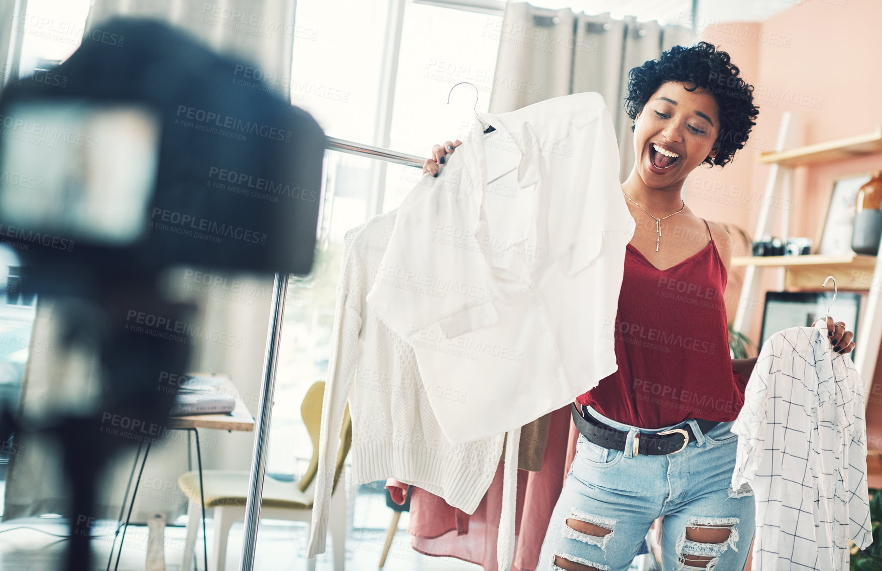 Buy stock photo Shot of a woman recording herself while holding up two clothing items