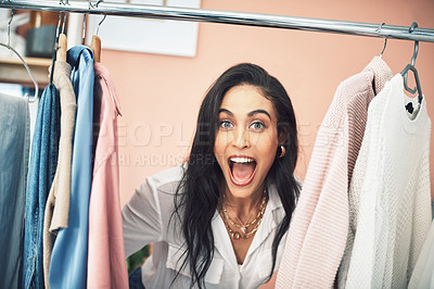 Buy stock photo Shot of a young woman sticking her head in between items on a clothing rail
