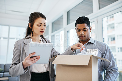 Buy stock photo Shot of a young businessman and businesswoman unpacking a box of computer equipment in a modern office