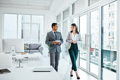 Buy stock photo Shot of a young businessman and businesswoman having a discussion while waking through a modern office