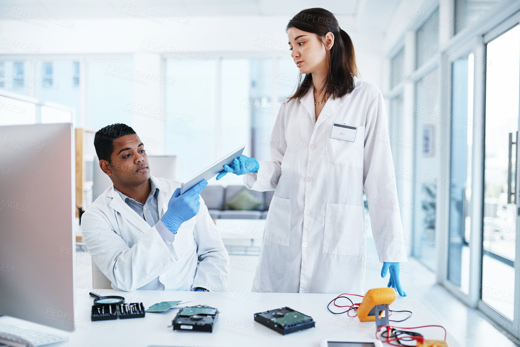 Buy stock photo Shot of a young man and woman repairing computer hardware in a laboratory