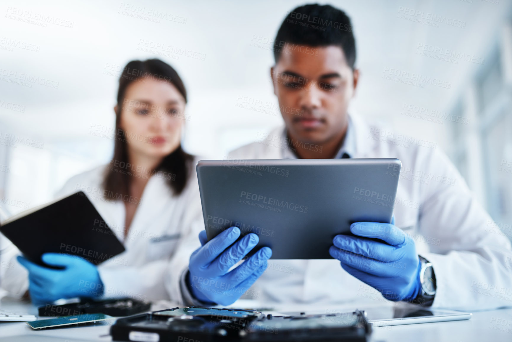 Buy stock photo Shot of a young man and woman using a digital tablet while repairing computer hardware in a laboratory