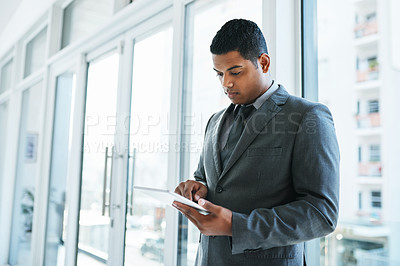 Buy stock photo Shot of a young businessman using a digital tablet in a modern office