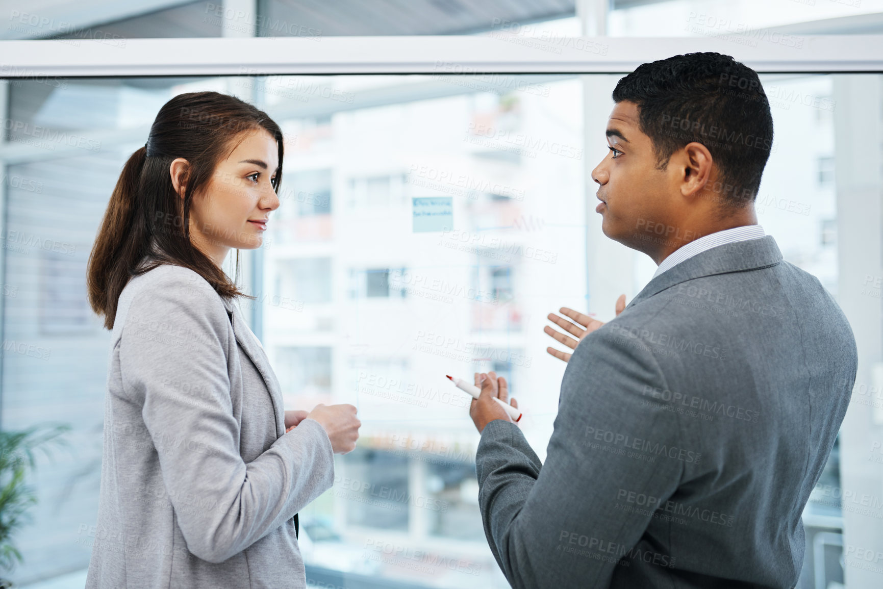 Buy stock photo Shot of a young businessman and businesswoman having a brainstorming session in a modern office