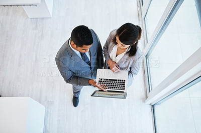 Buy stock photo High angle shot of a young businessman and businesswoman using a laptop in a modern office