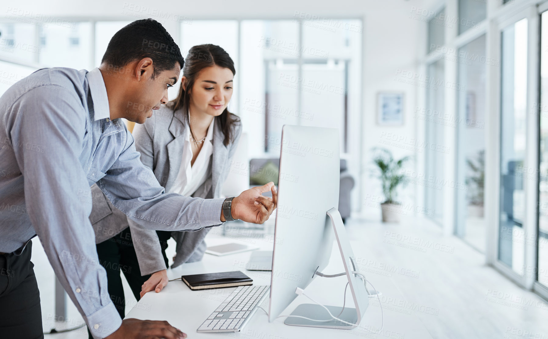 Buy stock photo Shot of a young businessman and businesswoman using a computer in a modern office