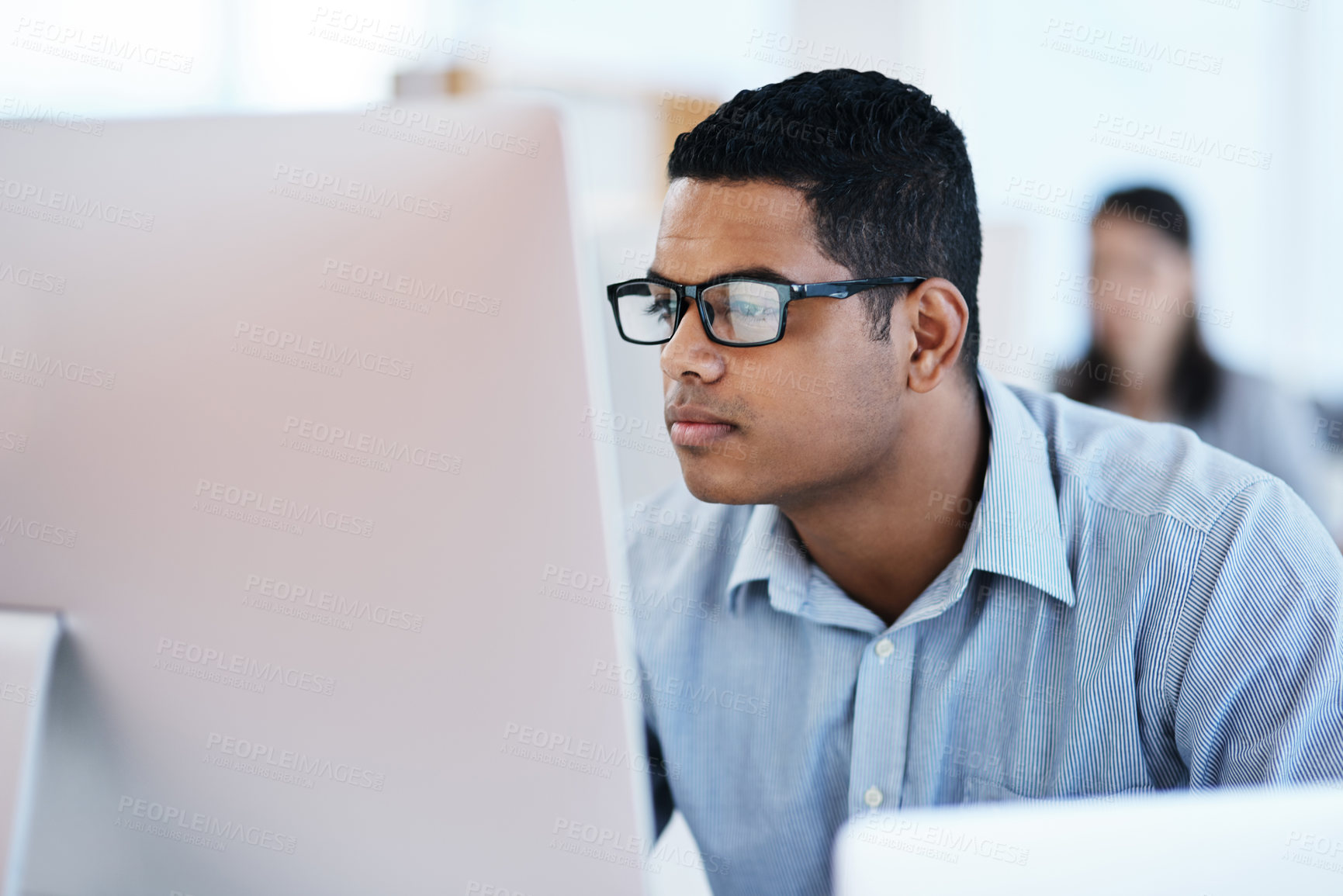 Buy stock photo Shot of a young businessman using a computer in a modern office