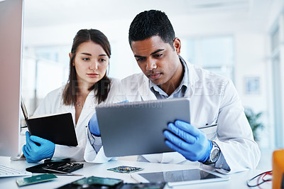 Buy stock photo Shot of a young man and woman using a digital tablet while repairing computer hardware in a laboratory