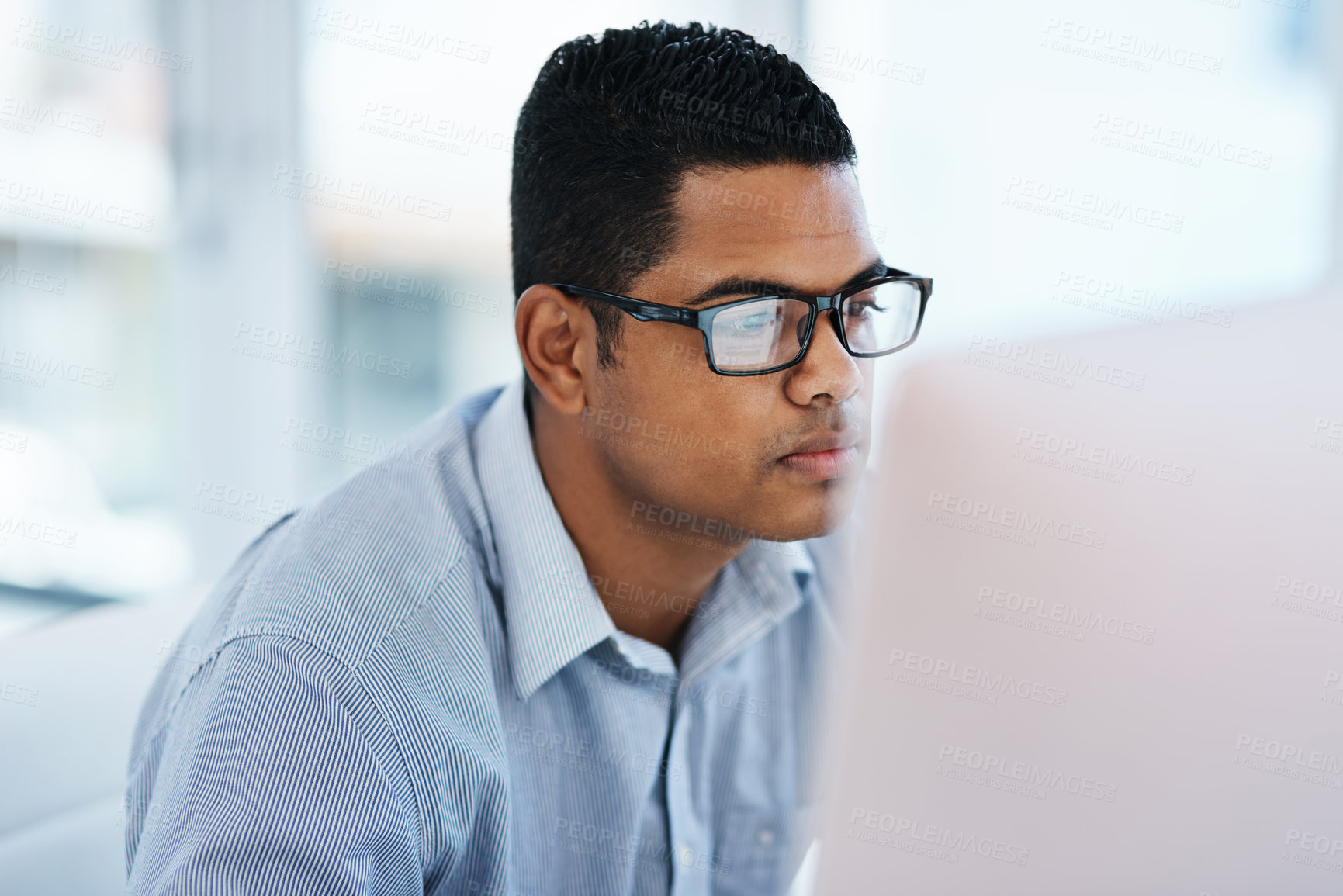 Buy stock photo Shot of a young businessman using a computer in a modern office