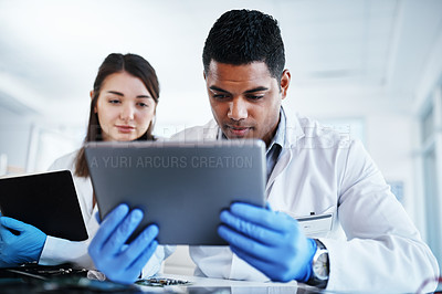 Buy stock photo Shot of a young man and woman using a digital tablet while repairing computer hardware in a laboratory