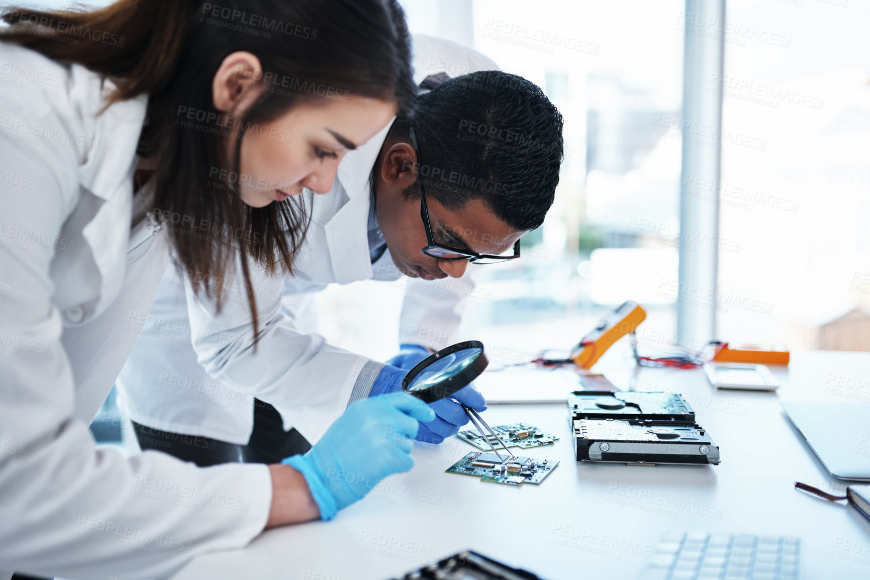 Buy stock photo Computer, hardware and people in lab with magnifying glass in motherboard maintenance, repair or engineering. IT, research and electronic technician with circuit board, tools and teamwork at desk.