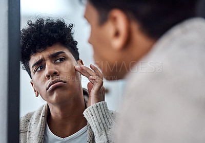Buy stock photo Shot of a handsome young man inspecting his face in the bathroom mirror