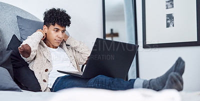 Buy stock photo Shot of a young man using a laptop on the bed at home