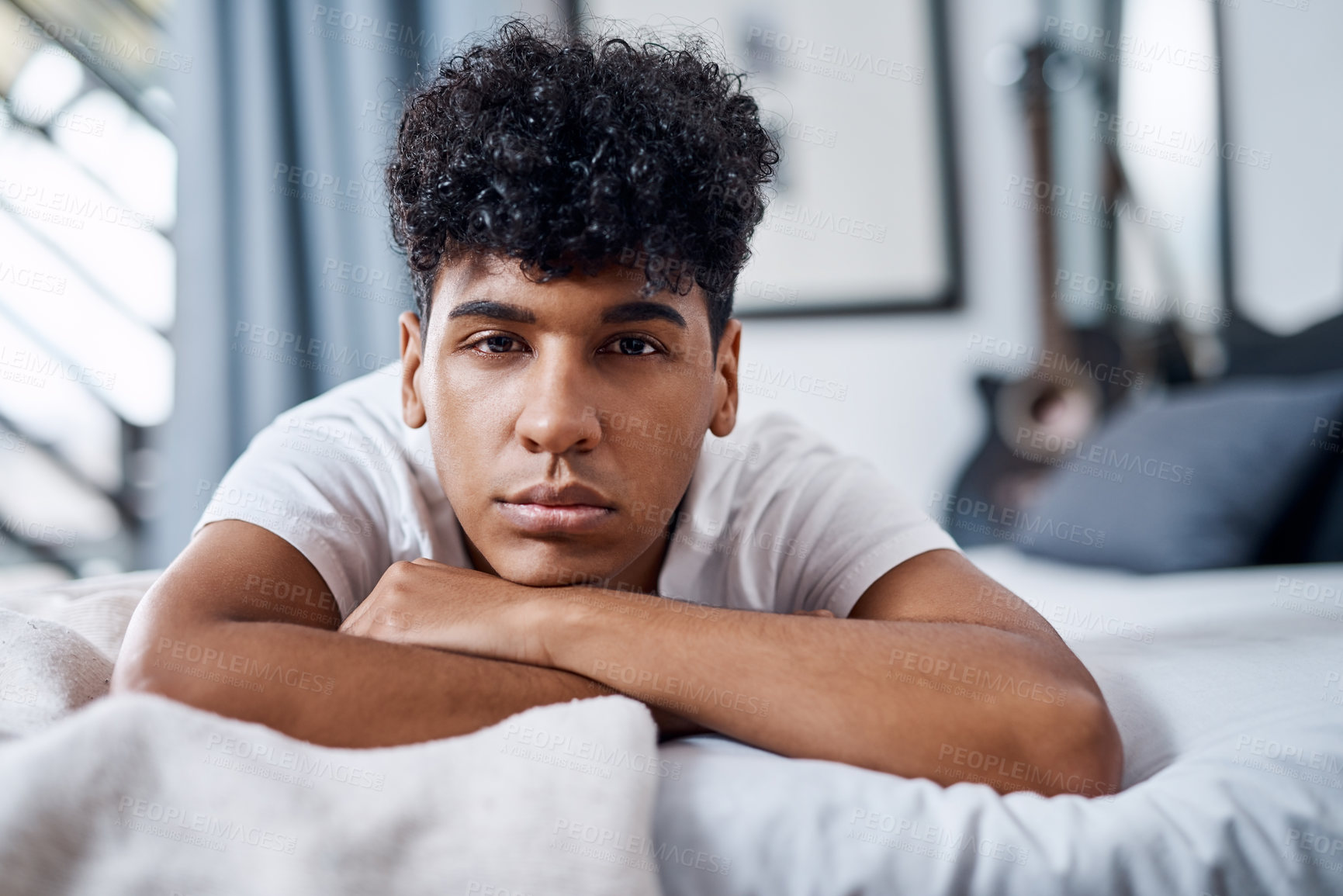 Buy stock photo Shot of a young man lying on his bed and looking bored
